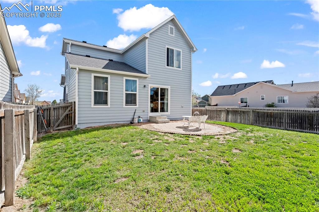 Rear view of property featuring a patio, a fenced backyard, roof with shingles, and entry steps
