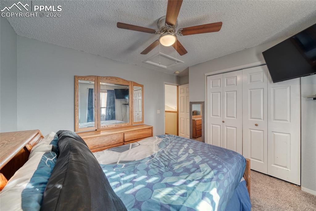 Bedroom with carpet, a ceiling fan, a textured ceiling, and a closet