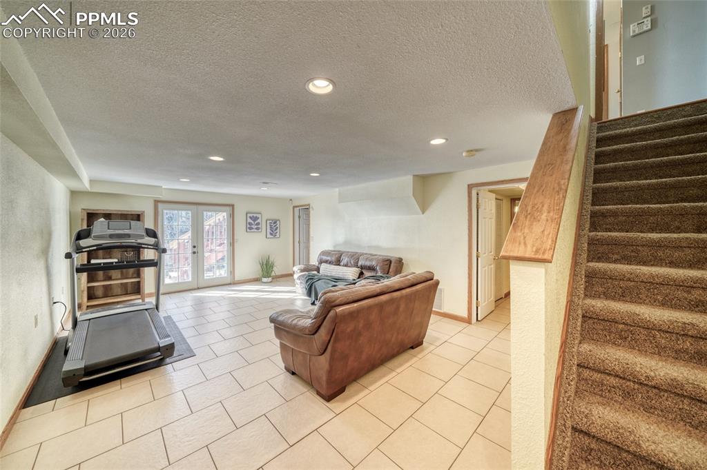Living area with a textured ceiling, light tile patterned floors, recessed lighting, and french doors