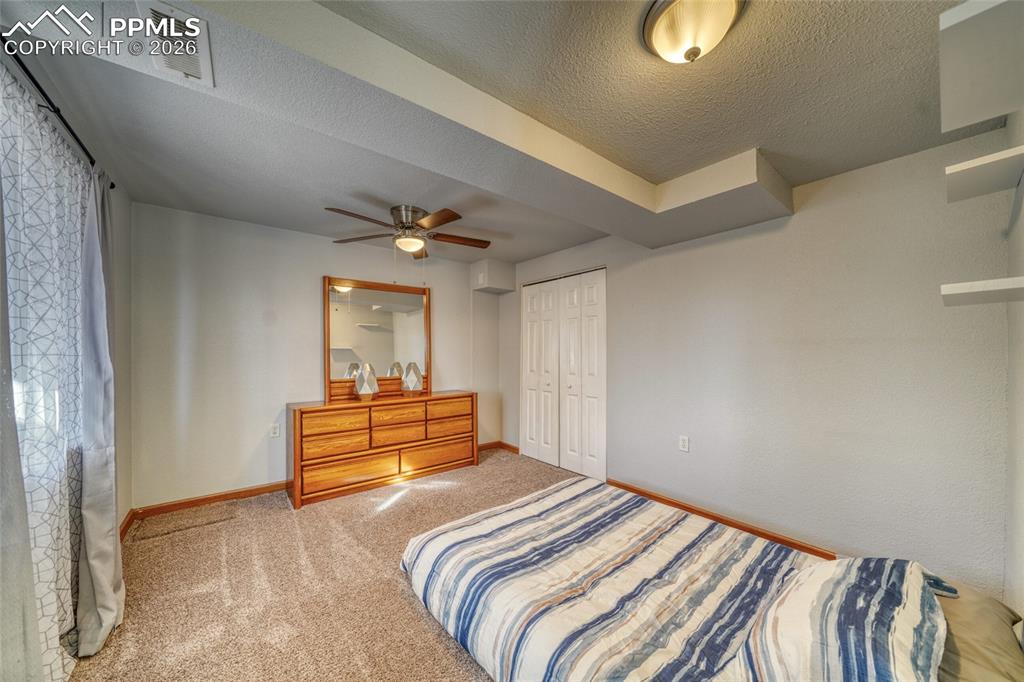 Carpeted bedroom featuring a textured ceiling, a closet, and a ceiling fan