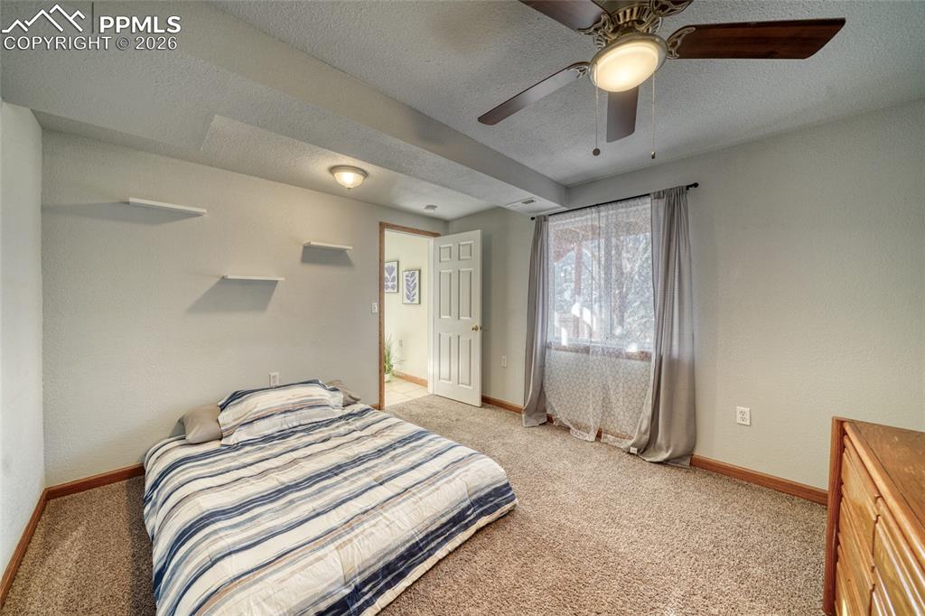 Bedroom featuring a textured ceiling, light colored carpet, and ceiling fan