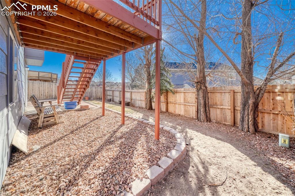 Fenced backyard with a wooden deck and a patio area