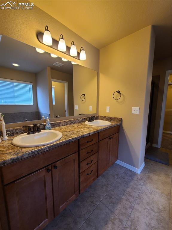 Bathroom featuring double vanity, dark tile patterned floors, and a closet