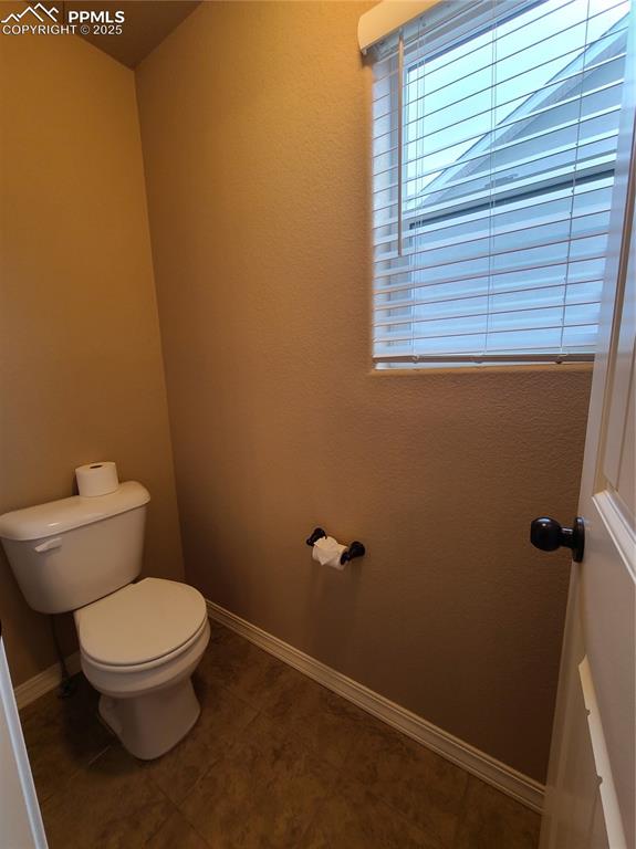Bathroom with toilet and dark tile patterned floors