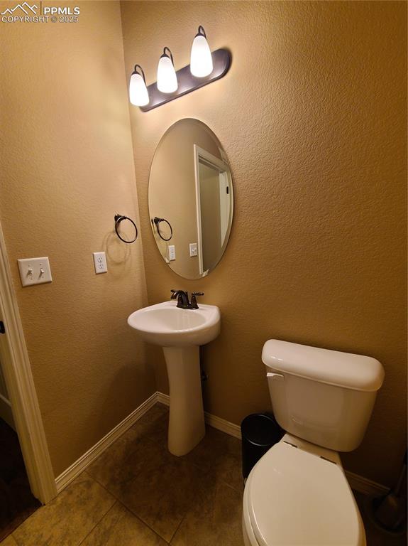 Half bath on main level featuring a textured wall and tile patterned flooring
