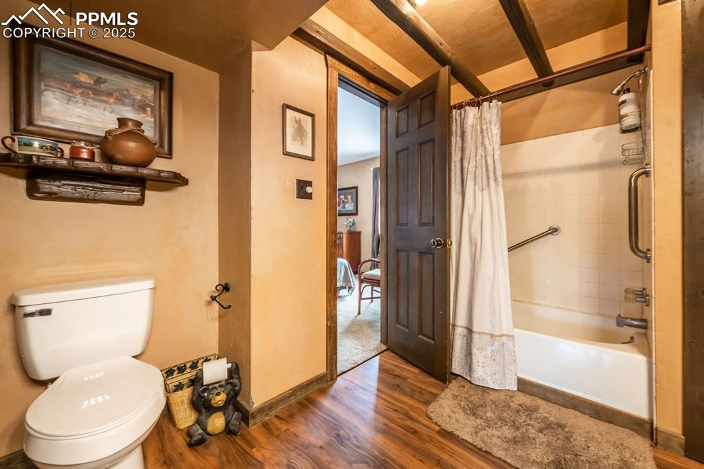 Bathroom featuring wood-type flooring, toilet, and shower / bath combo with shower curtain