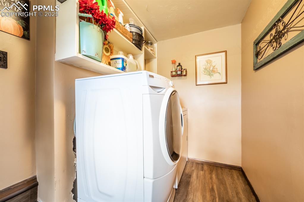 Clothes washing area featuring hardwood / wood-style flooring and washer and clothes dryer