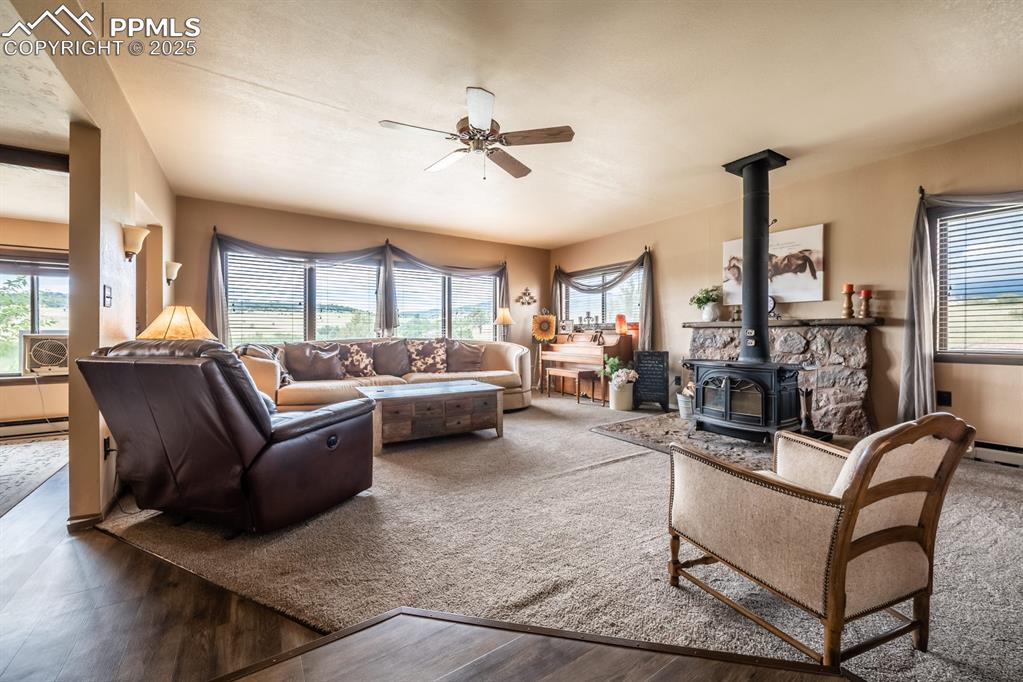 Living room featuring a wood stove, ceiling fan, cooling unit, and dark wood-type flooring