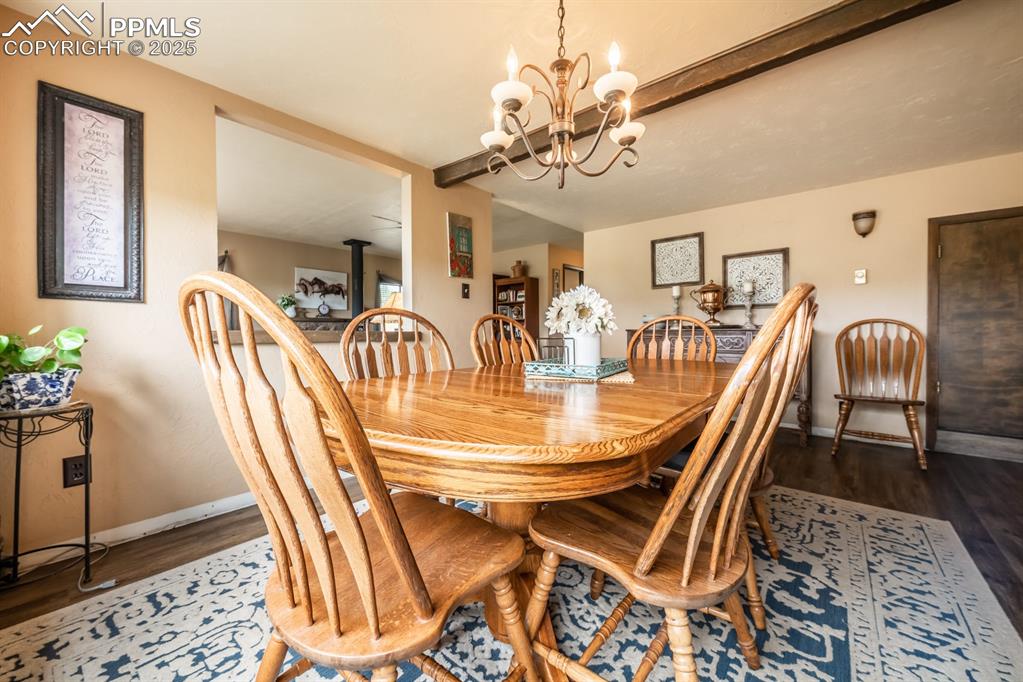 Dining area featuring a wood stove, dark wood-type flooring, and a notable chandelier