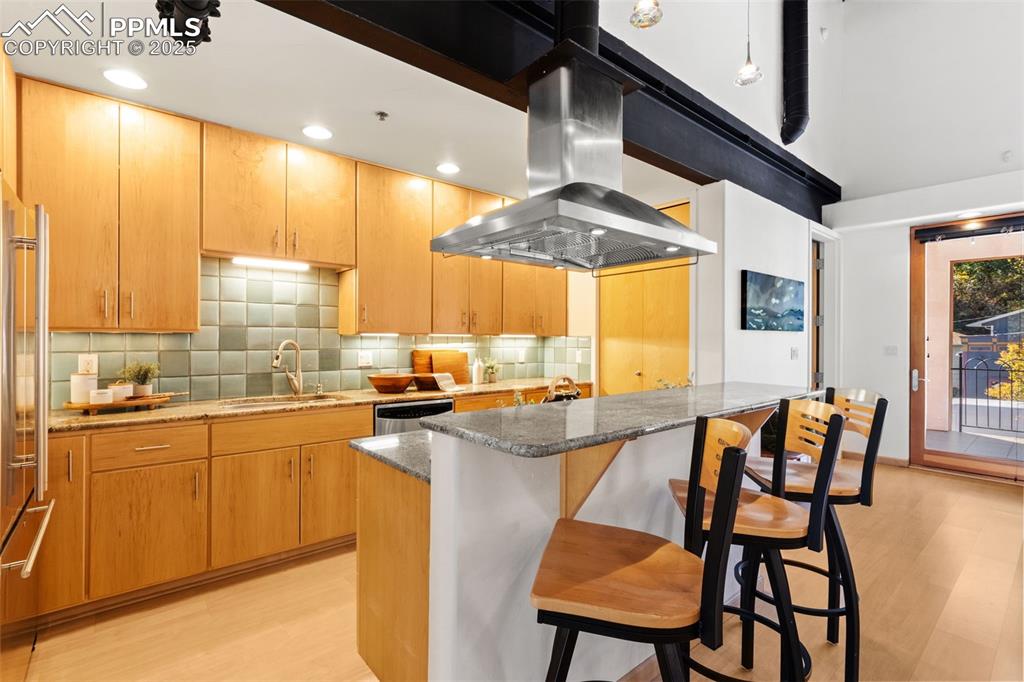Kitchen with stone counters, stainless steel appliances, an island with breakfast bar seating