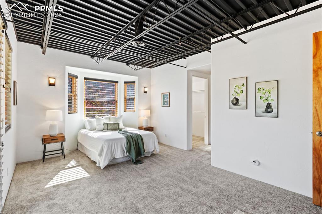 Newly carpeted bedroom with industrial style ceiling, and natural lighting