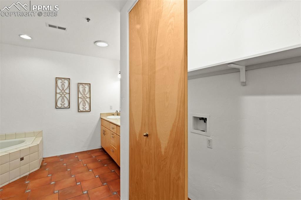 Bathroom with unique stone flooring and washer & dryer hookups in closet
