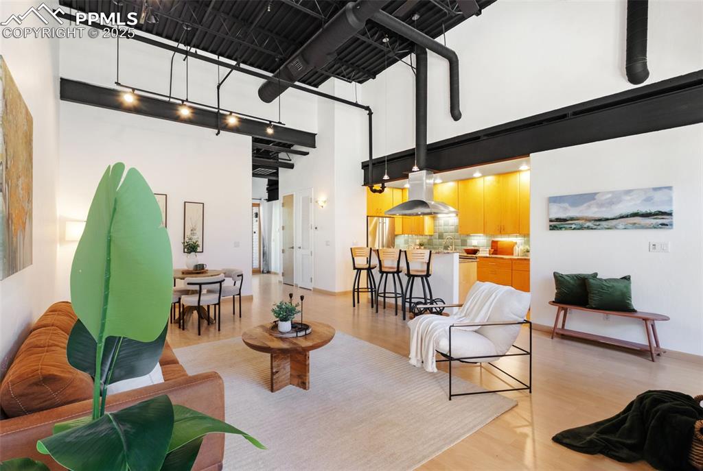 Open floor plan of living room , dining area, and kitchen. The loft features high ceiling and light wood-style floors
