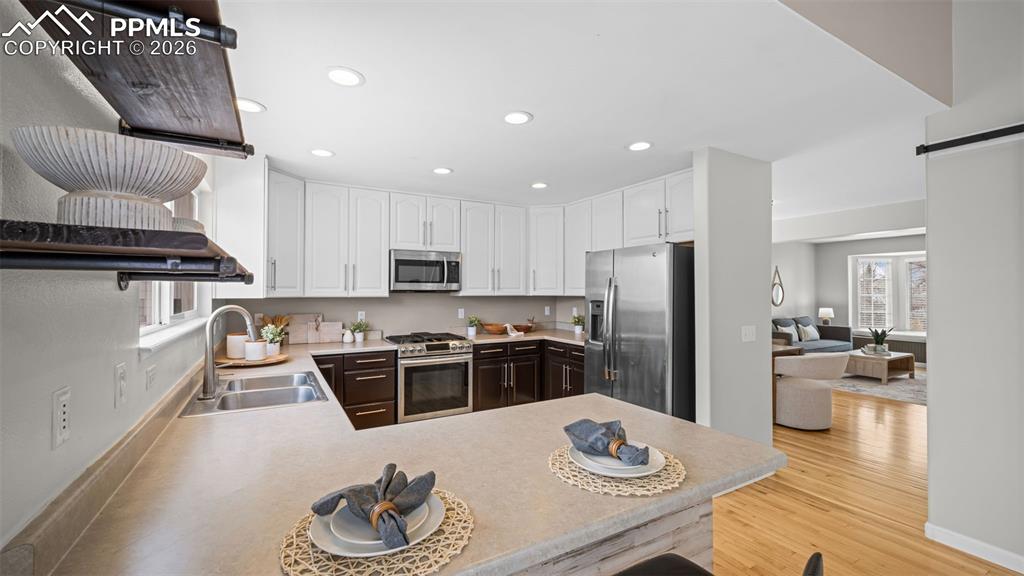 Kitchen featuring a peninsula, white cabinetry, stainless steel appliances, plenty of natural light, and recessed lighting