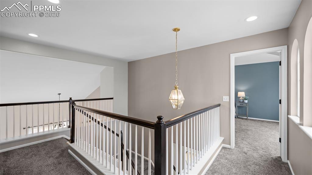 Hallway with carpet, an upstairs landing, and recessed lighting