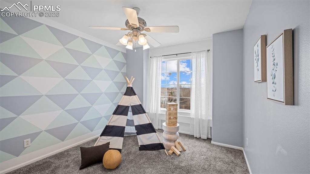 Playroom with carpet, an accent wall, and a ceiling fan