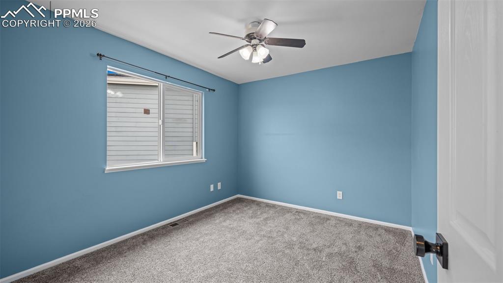 Carpeted spare room with a ceiling fan and baseboards
