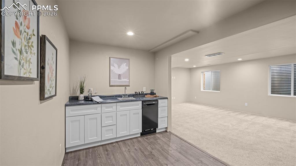 Indoor wet bar featuring recessed lighting, light wood-style floors, black dishwasher, and white cabinets