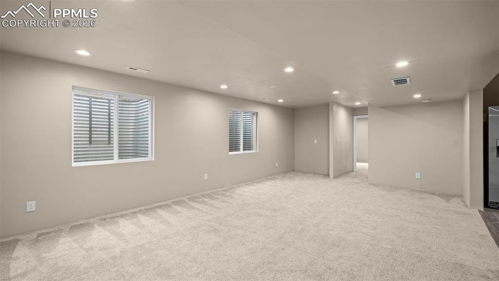 Basement featuring recessed lighting, light colored carpet, and stainless steel fridge