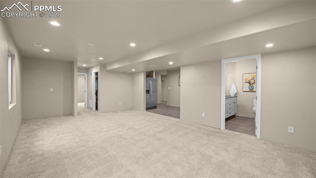 Finished below grade area featuring recessed lighting, stainless steel fridge, and light carpet