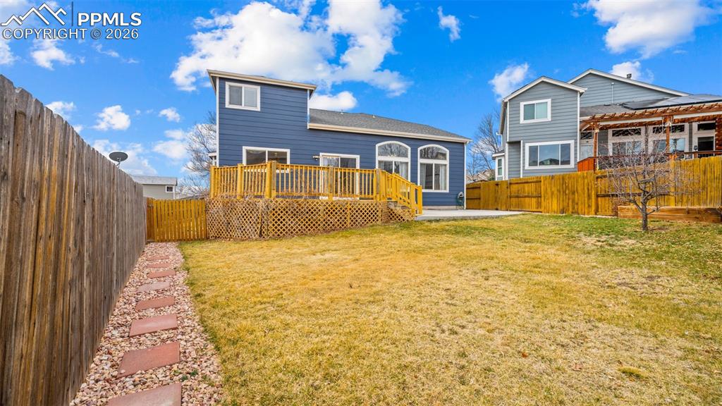 Rear view of property with a fenced backyard, a wooden deck, and a patio area