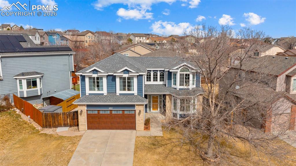 Traditional home featuring driveway, an attached garage, brick siding, a shingled roof, and a residential view