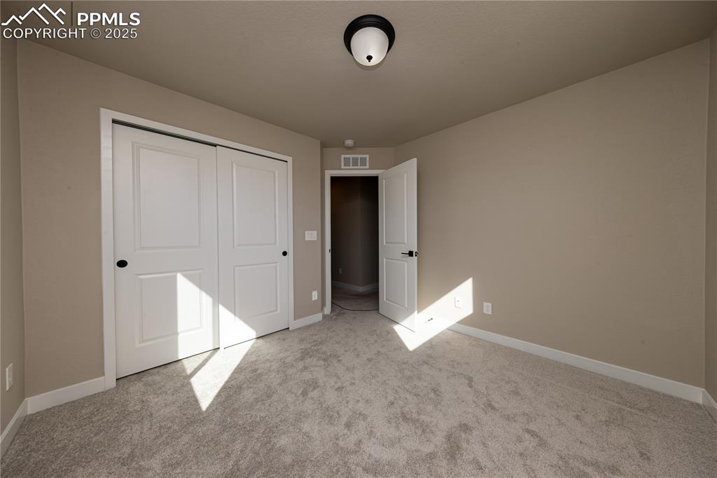 Unfurnished bedroom featuring light carpet and a closet
