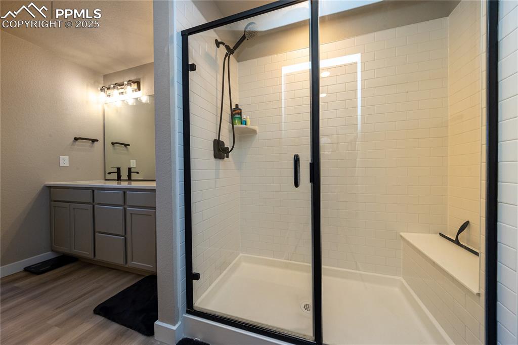 Bathroom with vanity, a stall shower, light wood-type flooring, and a textured wall