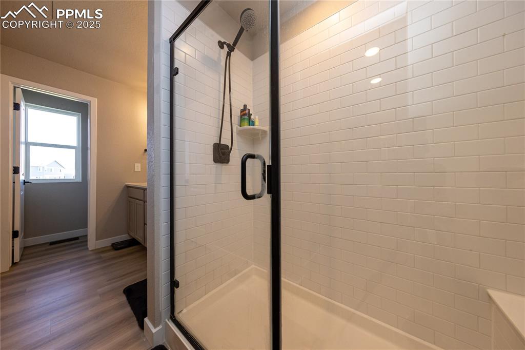 Bathroom with a shower stall, vanity, and dark wood-style floors