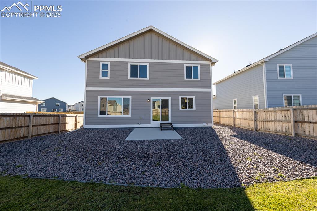 Rear view of house with a patio, board and batten siding, and a fenced backyard