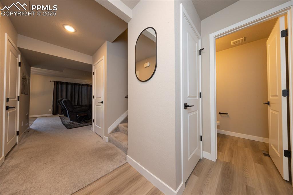 Hall with light wood finished floors, stairway, and recessed lighting