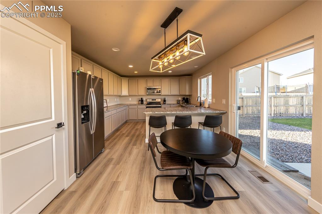 Kitchen with decorative light fixtures, appliances with stainless steel finishes, light wood finished floors, recessed lighting, and a chandelier