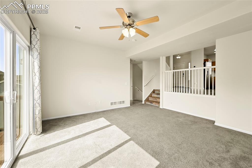Unfurnished room with stairway, carpet floors, and ceiling fan