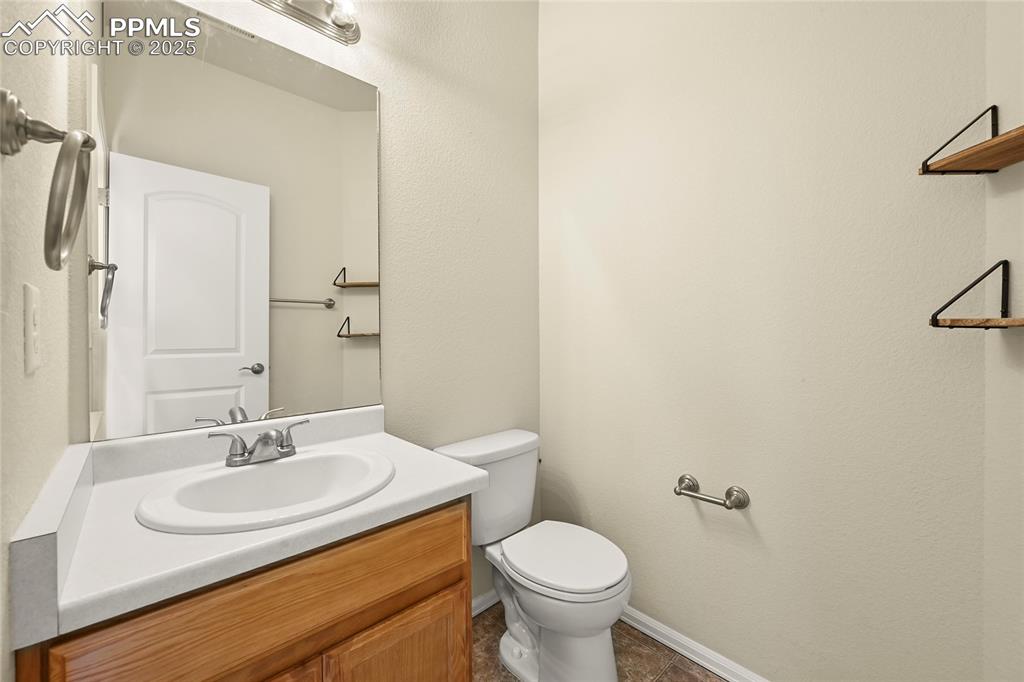 Bathroom featuring vanity, a textured wall, and dark tile patterned flooring