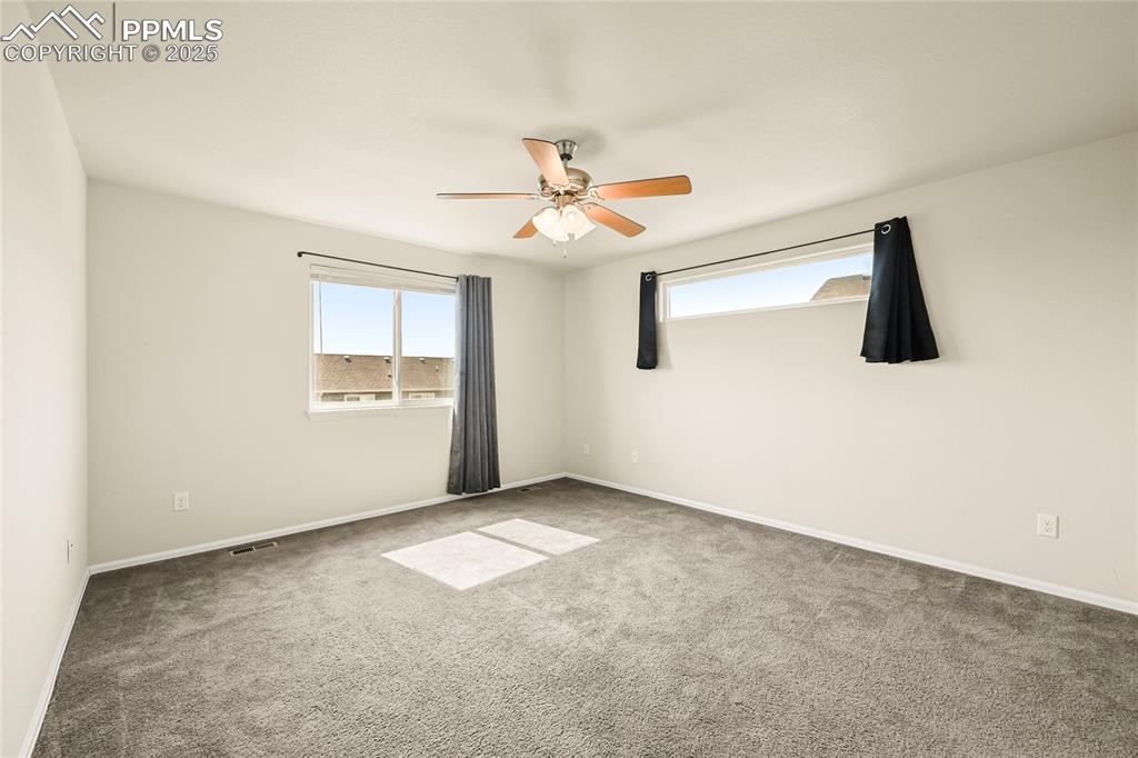 Carpeted empty room featuring baseboards and a ceiling fan