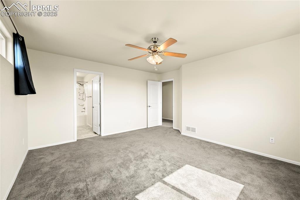 Unfurnished bedroom with carpet floors, a ceiling fan, and ensuite bathroom