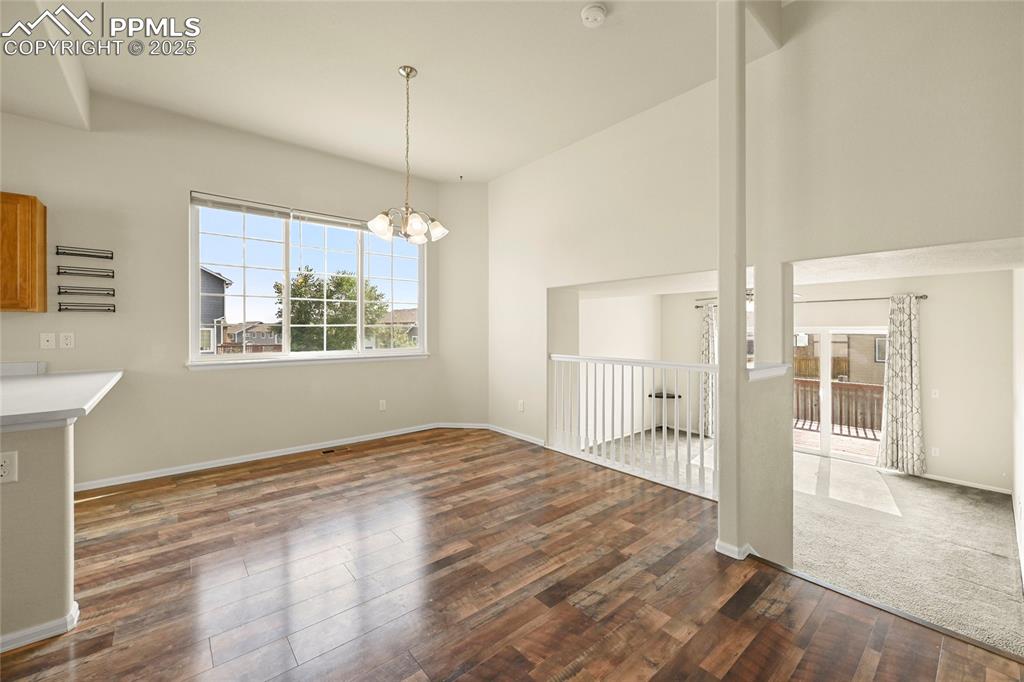 Unfurnished dining area featuring a chandelier and dark wood finished floors