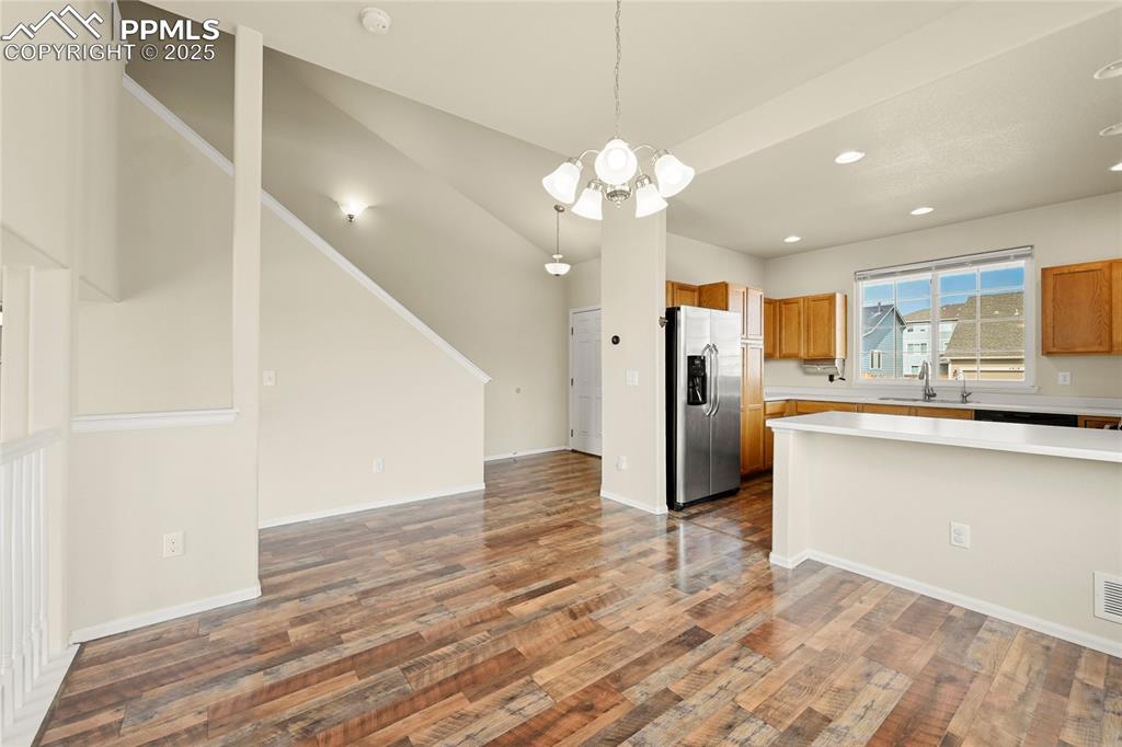 Kitchen with decorative light fixtures, open floor plan, light countertops, stainless steel fridge with ice dispenser, and a chandelier