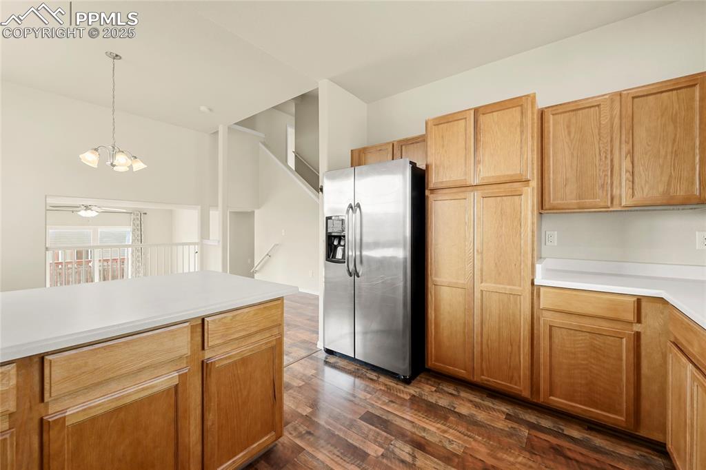 Kitchen with stainless steel refrigerator with ice dispenser, light countertops, dark wood finished floors, pendant lighting, and a chandelier