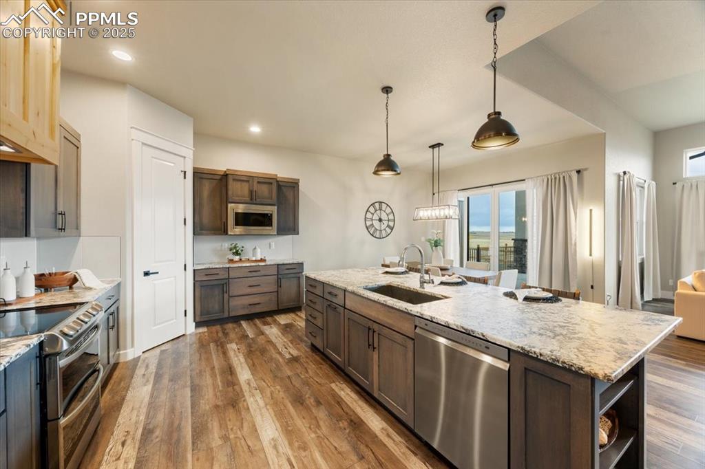 Kitchen featuring appliances with stainless steel finishes, a wealth of natural light, dark wood finished floors, and a sink