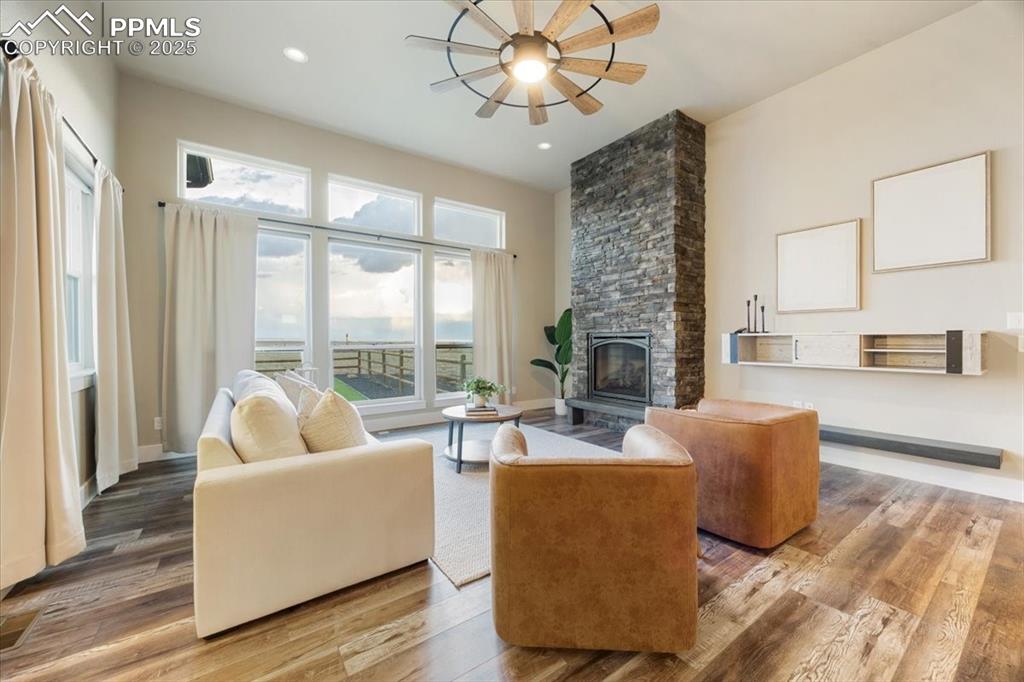 Living room featuring wood finished floors, recessed lighting, and a stone fireplace