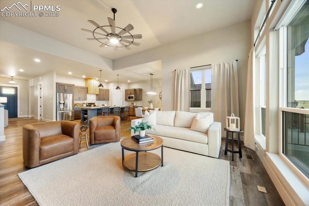 Living area with dark wood-type flooring, ceiling fan, a healthy amount of sunlight, and recessed lighting