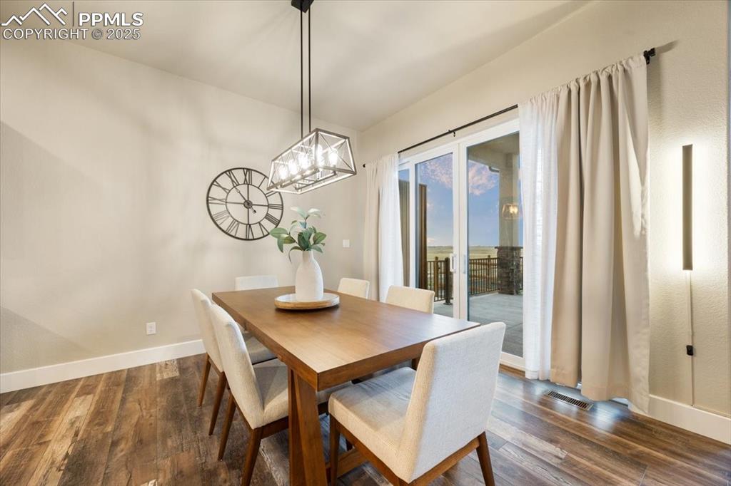 Dining area with dark wood-style floors, an inviting chandelier, visible vents, and baseboards