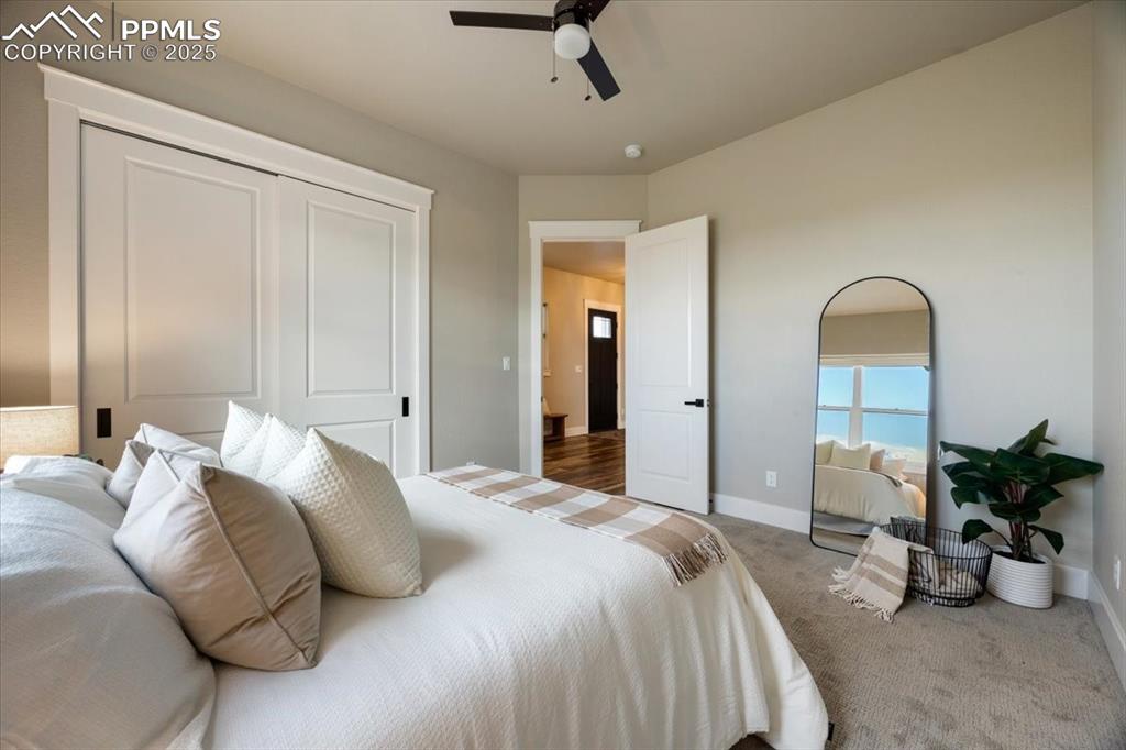 Carpeted bedroom with baseboards, ceiling fan, and a closet