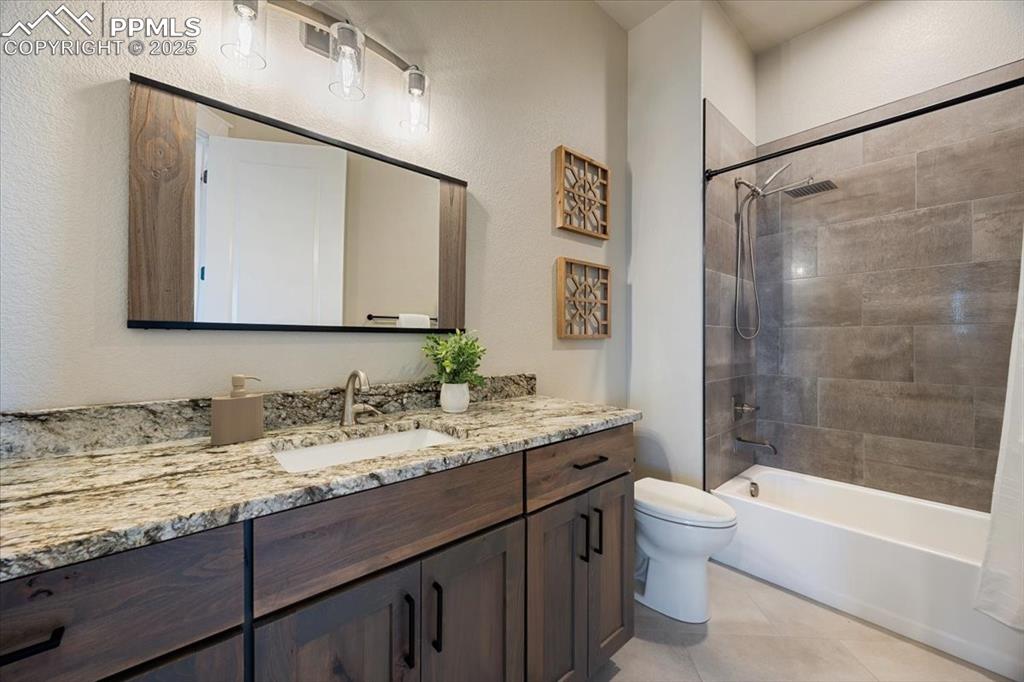 Bathroom with washtub / shower combination, toilet, tile patterned flooring, and vanity