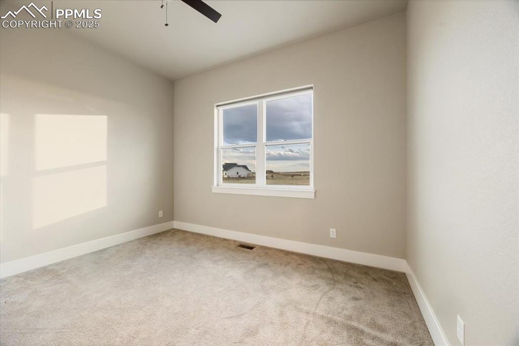 Carpeted spare room featuring a ceiling fan and baseboards