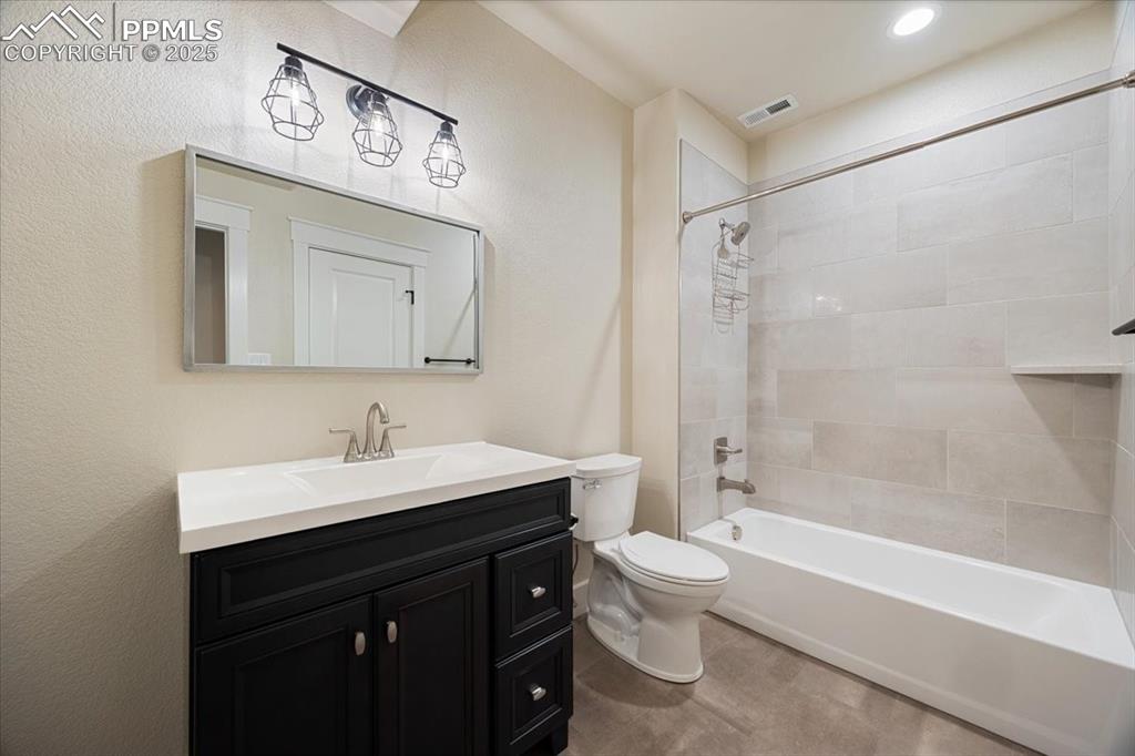 Full bathroom with toilet, visible vents, shower / bath combination, and vanity