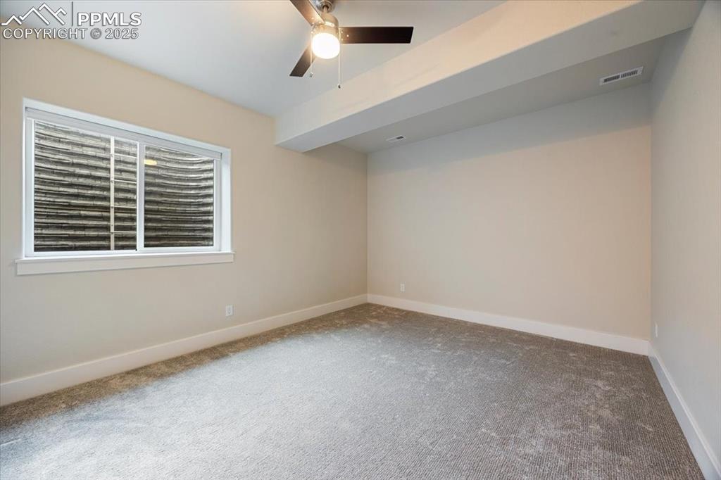 Spare room with a ceiling fan, visible vents, carpet floors, and baseboards