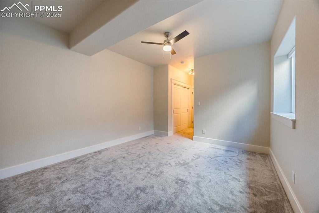 Carpeted spare room with baseboards and a ceiling fan