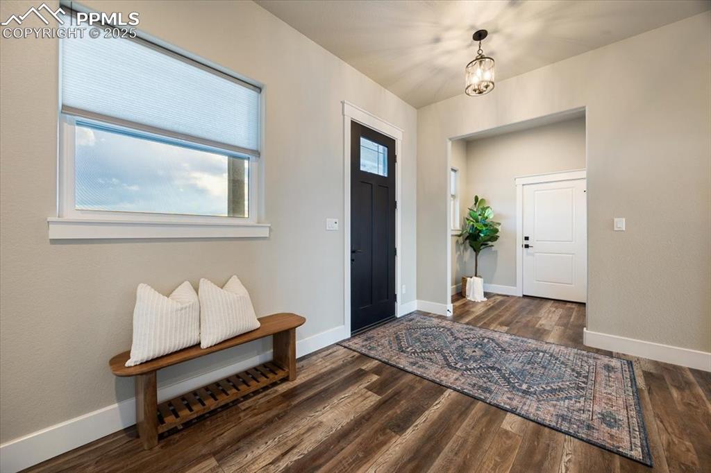 Foyer entrance featuring baseboards, wood finished floors, and an inviting chandelier